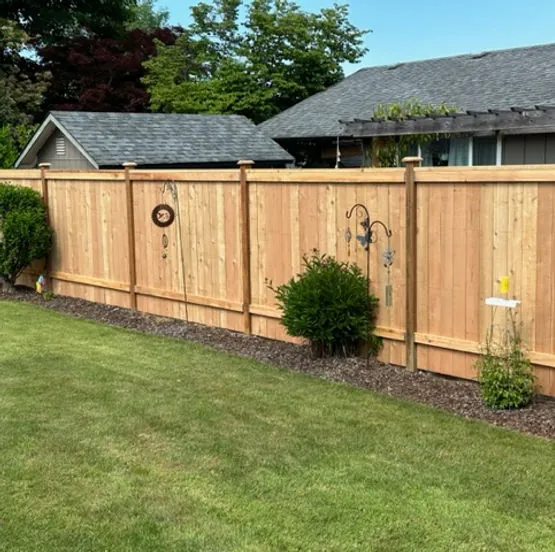 Cedar privacy fence with decorative post caps installed in backyard